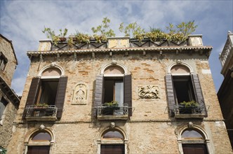 Venice, Veneto, Italy. Building facade with multiple windows each with small balcony window box and