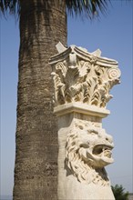 Selcuk, Izmir Province, Turkey. Corinthian column with protective lion mask beneath palm tree at