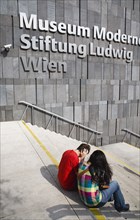 Vienna, Austria. Neubau District. Young student couple sitting on the steps of the Museum of Modern