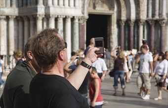 Venice, Veneto, Italy. Centro Storico St. Marks Square Tourist takes photograph on mobile phone