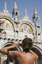Venice, Veneto, Italy. Centro Storico St. Marks Square Tanned female tourist wearing backless top