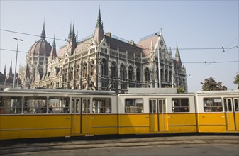 Budapest, Pest County, Hungary. Yellow tram passing the Parliament Building. Hungary Hungarian