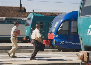 Venice, Veneto, Italy. Commuters running to board local train with regional trains on platforms at
