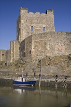 Carrickfergus, County Antrim, Ireland. Castle exterior with a boat moored in the foreground.