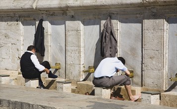 Istanbul, Turkey. Sultanahmet. The New Mosque or Yeni Camii. Two men washing and making ablutions