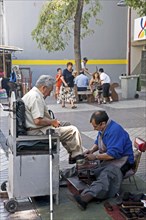 Santiago, Chile. Shoe-shine in downtown shopping area. Partially sighted or blind elderly man