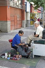 Santiago, Chile. Elderly man at street shoe shine in downtown shopping area piles of shoe polish