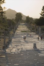 Selcuk, Izmir Province, Turkey. Ephesus. Tourists on paved road lined by broken columns in late