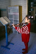 Sariwon, Hwanghae Province, North Korea. Young girl standing in front of music stand playing the