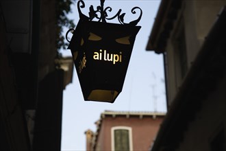 Venice, Veneto, Italy. Centro Storico Lantern outside restaurant inscribed with ai lupi which