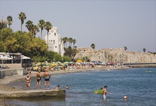 Kos, Dodecanese Islands, Greece. Kos Town beach with castle walls and harbour entrance behind and