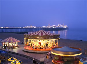 Brighton, East Sussex, England. Seafront amusements and Brighton Pier illuminated at night. Great