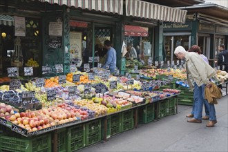 Vienna, Austria. The Naschmarkt. Customers at fresh produce stall looking at display that includes