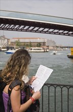 Venice, Veneto, Italy. Female tourist looking at map in front of Ponte di Calatrava Bridge the