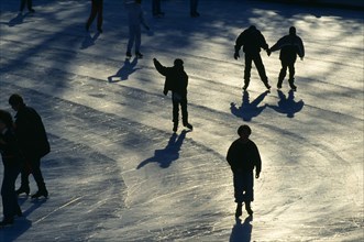 New York, New York, USA. Central Park ice skaters casting long shadows Kids North America United