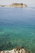 Kusadasi, Aydin Province, Turkey. View towards Guvercin Ada or Pigeon Island across clear turquoise