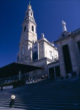 Fatima, Beira Litoral, Portugal. Woman wearing hat seated by steps beneath the church Female Women