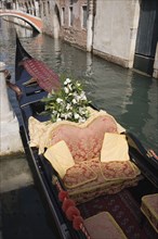 Venice, Veneto, Italy. Gondola prepared for wedding with red and gold brocade seating and flowers