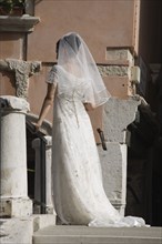 Venice, Veneto, Italy. Bride in white wedding dress and veil standing on canal bridge in late