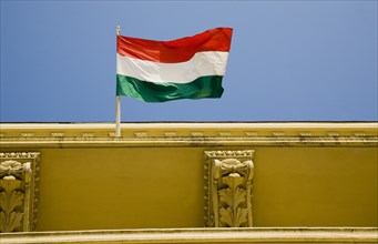Budapest, Pest County, Hungary. Hungarian flag flying from top of partly seen renovated building on