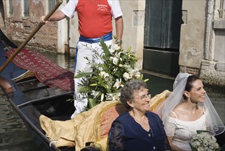 Venice, Veneto, Italy. Cropped shot of gondolier steering decorated gondola with smiling bride in