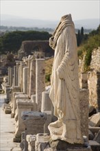 Selcuk, Izmir Province, Turkey. Ephesus. Headless statue on plinth in line of ruined pillars and