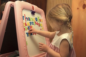 Young girl Sarah Bleau using magnetic letters on dry erase board in Keene New Hampshire. Education
