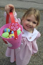 Young girl Sarah Bleau holding up basket of Easter eggs collected on Easter egg hunt in Keene New