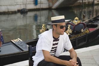 Venice, Veneto, Italy. Centro Storico Young gondolier in traditional uniform of striped shirt and