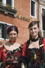 Venice, Veneto, Italy. Portrait of two young women wearing traditional costume to promote Venice