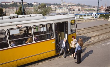 Budapest, Pest County, Hungary. Tram with passengers alighting and view towards the River Danube