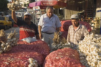 Kusadasi, Aydin Province, Turkey. Stallholder selling garlic at weekly market standing behind stall
