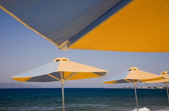 Kos, Dodecanese Islands, Greece. Blue and yellow striped parasols on beach outside Kos Town. Greece
