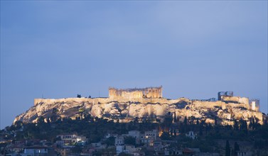Athens, Attica, Greece. View towards the Acropolis on hilltop above Athens illuminated at dusk.