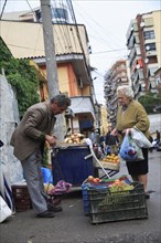 Albania, Tirane, Tirana, A street vendor using hand held set of scales to weigh fruit for elderly