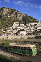 Albania, Berat, Traditional Ottoman buildings on hillside above the River Osum with local bus in