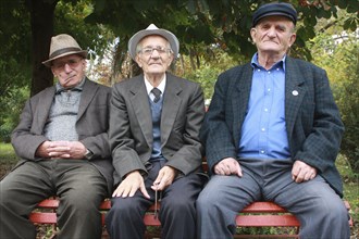 Albania, Berat, Portrait of three elderly men sitting on a park bench.