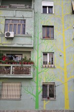 Albania, Tirane, Tirana, Part view of exterior facade of apartment block painted with tree forms in