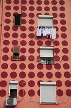 Albania, Tirane, Tirana, Part view of apartment block painted pink with pattern of red circles.