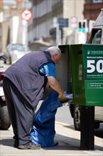 Ireland, County Dublin, Dublin City, An Post Irish postal worker emptying mail from a green modern
