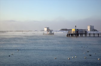 England, West Sussex, Shoreham-by-Sea , Mist rising from harbour waters on frosty morning with tug