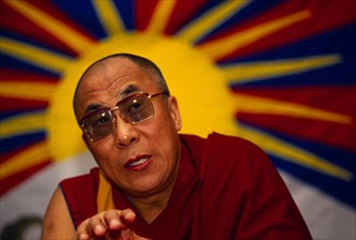 China, Tibet, Buddhism, The 14th Dalai Lama speaking to followers. Vibrant image of a yellow sun in