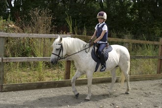 Sport, Equestrian, Horse Riding, A young girl riding her pony in outdoor sand school.