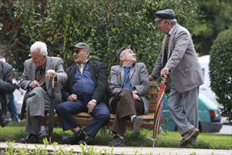 Albania, Tirane, Tirana, Group of elderly men and pensioners talking on a park bench.