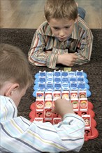 Children, Games, Indoor, Two young boys playing a game of Guess Who. together.