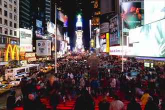 USA, New York, New York City, Manhattan  People sitting on lit red steps or walking at night in