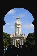 Ireland, County Dublin, Dublin City, Trinity College university with people walking through an arch