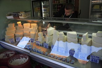 Albania, Tirane, Tirana, Cheese shop in the Avni Rustemi Market with young male vendor behind