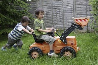 Children, Playing, Outdoors, Two twin boys aged six years old playing outside in a garden on a toy