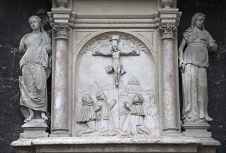 Stone relief carving of the crucifixion flanked by statues on the outside of the Stephansdom